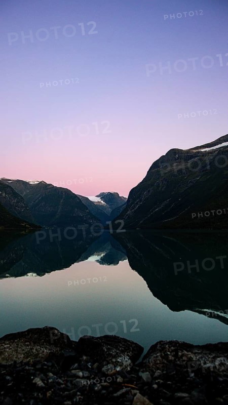A calm lake reflects the surrounding mountains at sunset, under a pink sky, evening mood on the lakeside, Nord-Trondelag Steinkjer, Norway, Scandinavia