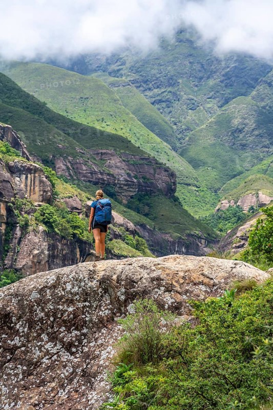 Female hiker standing in front of landscape with mountains and fog, Drakensberg National Park, KwaZulu Natal, South Africa