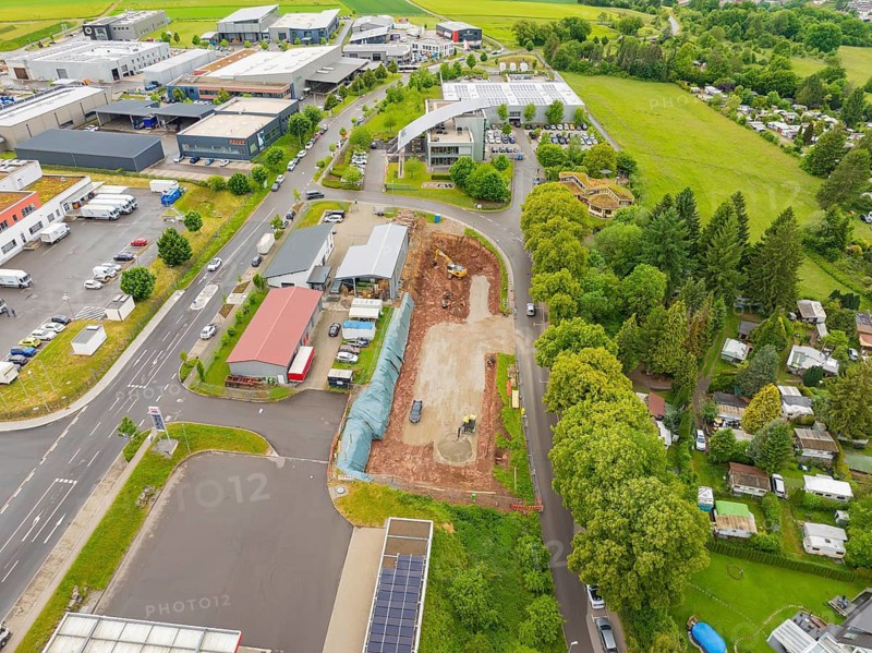 Industrial buildings and a construction site with surrounding roads and forests from the air in summer weather, Parkhaus Bau, Calw, Germany