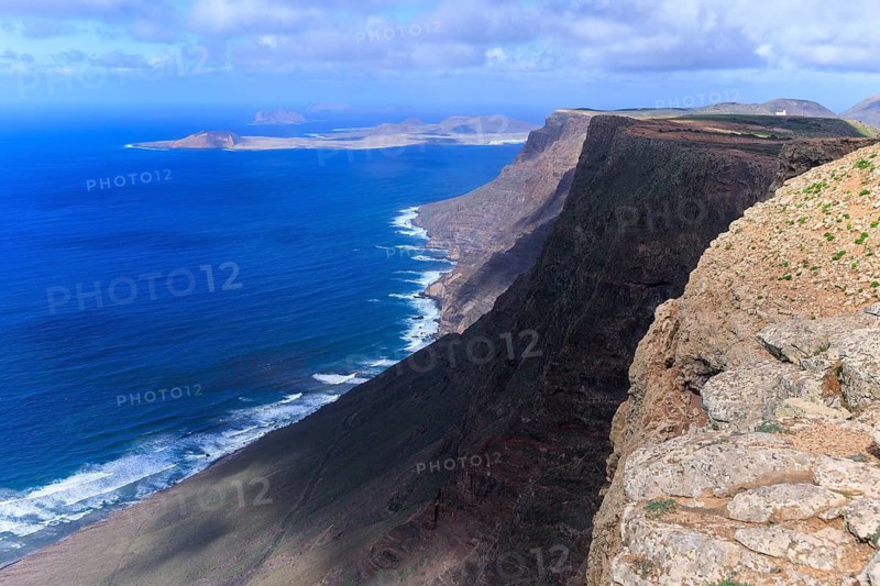Lanzarote, Canary Islands, Spain, Europe, Mirador de El Risco de Famara, Parque El Bosquecillo, Epic view of high cliffs that stretch dramatically across the blue sea and distant islands
