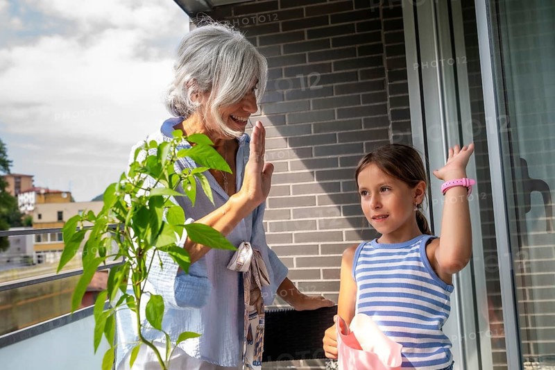 Happy grandmother and granddaughter interacting on a sunny balcony, celebrating family connection, expressing joy and affection, fostering intergenerational bonding and communication