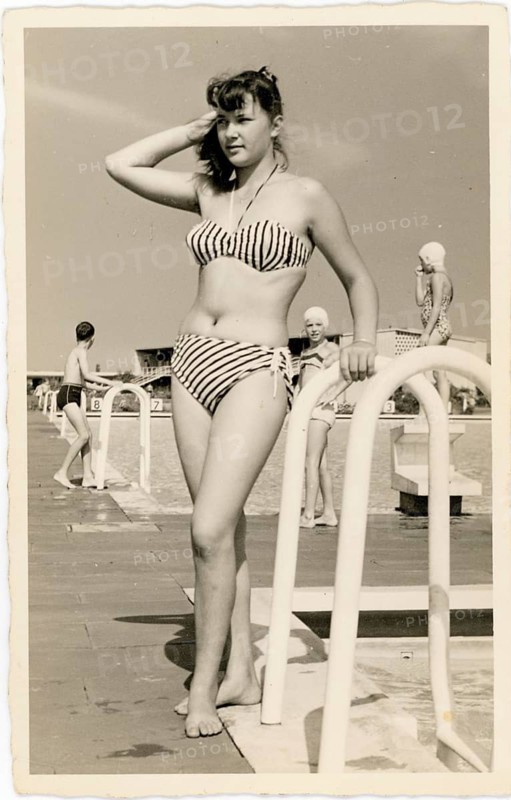Bathing, swimwear, leisure, summer, outdoor pool, woman in striped bikini leaning on the railing of a pool, looks calmly into the distance, around 1965