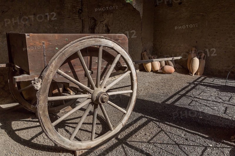 Old wooden cart and ceramic jugs on display inside an unenclosed building at the ancient ruins of Pompeii, Campania region, Italy