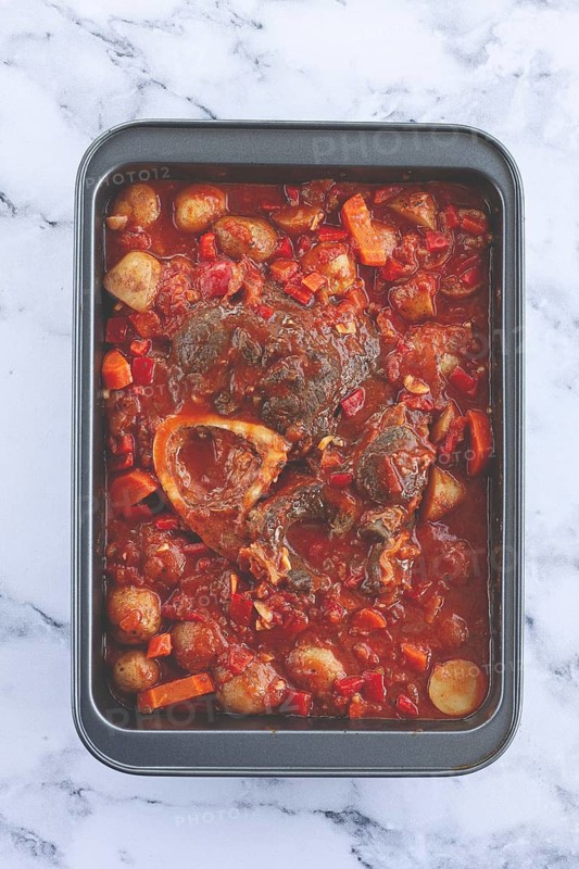 Ossobuco stew with vegetables, knuckle on the bone with new potatoes, in tomato sauce, homemade, top view, no people