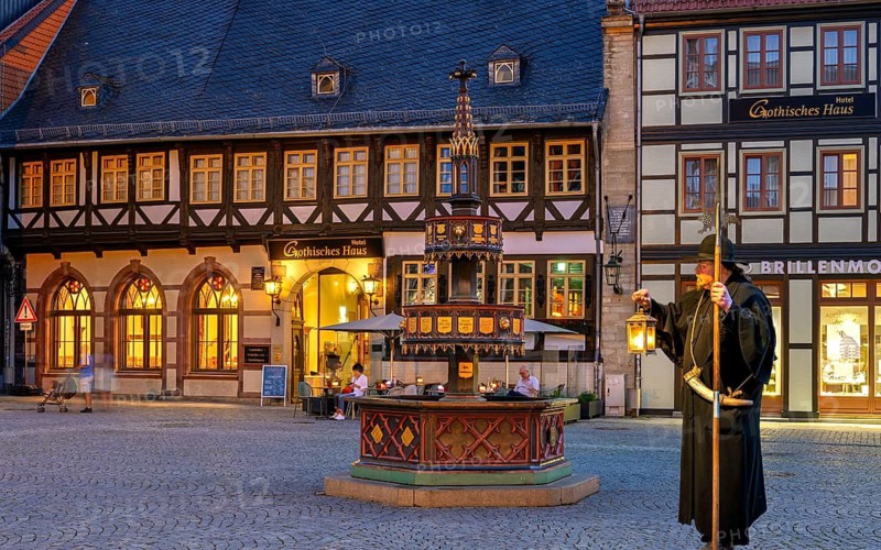 Night watchman in front of Wohntäterbrunnen illuminates Wernigerode Harz Germany