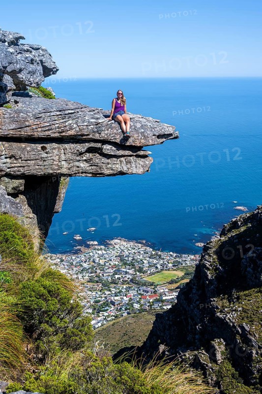 Young woman sitting on an imposing rock pin on a cliff, view of sea and coast, Kasteelspoort hiking, Table Mountains, Eastern Cape, Cape Town, South Africa