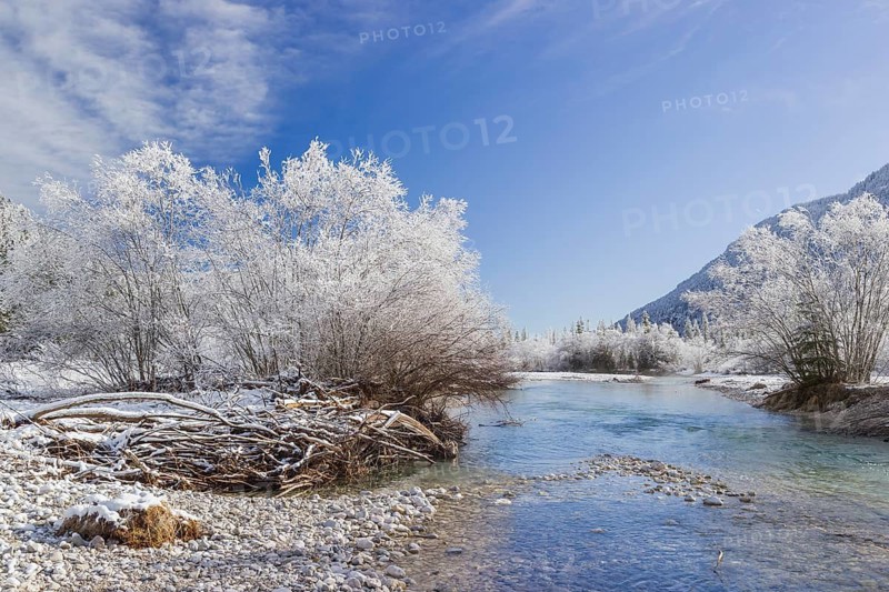 Isar valley in winter at temperatures of minus 18 degrees Celsius. Snow covered landscape with the Isar river flowing through. Some hoar frosted trees. Early morning