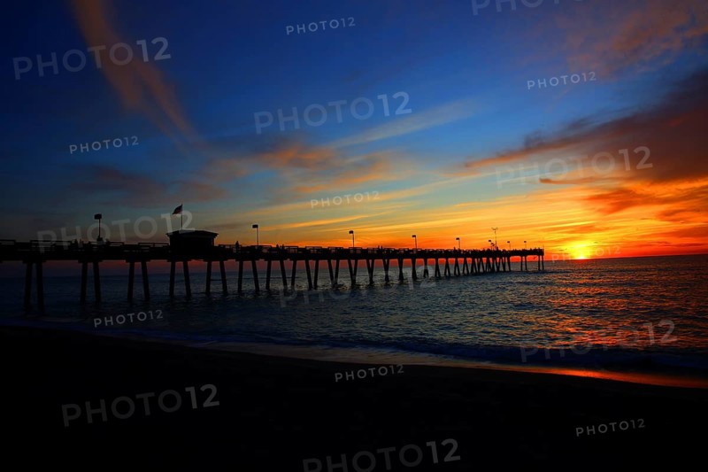 A pier against a colorful sky at sunset, calm sea and carefree atmosphere, Naples pier on the beach at sunset in Naples, Florida, USA