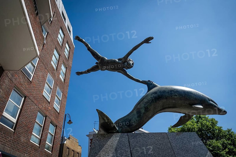 Modern sculpture boy with dolphin by David Wynne against a blue sky, Chelsea Embankment, London, Great Britain, England, Great Britain