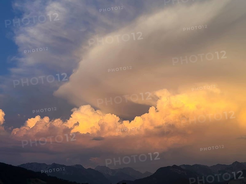 Evening sky at sunset with high strip-shaped cloud formations oriented in the form of arrows such as arrows in the shape of arrows indicate strong wind or weather changes on the edge of Alpine mountains, including Cumulus cluster clouds, Bavaria, Germany