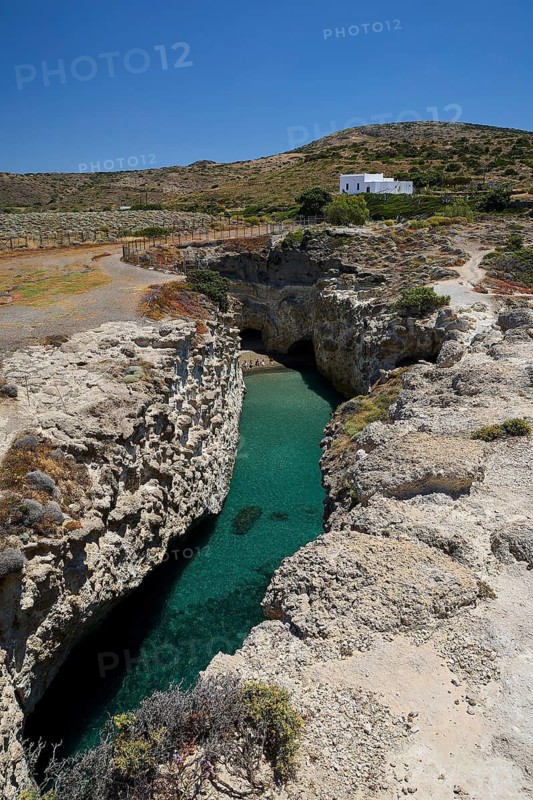 Rocky landscape with clear water and small white house under blue sky, volcanic island, island, Milos, Cyclades, Greek Islands, Greece