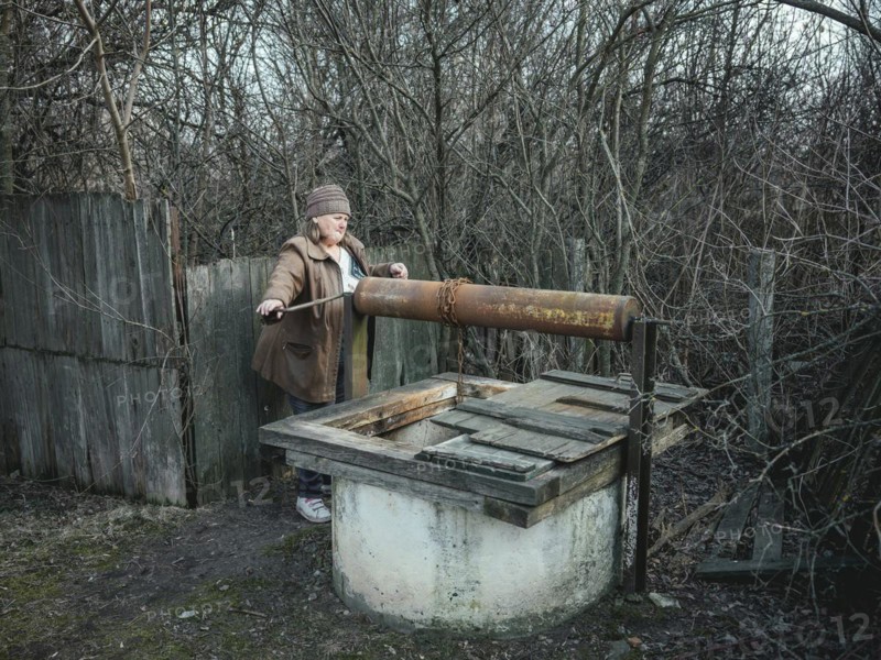 Larisa draws water from a well in Borshchivka. The village was under Russian occupation. She hid with her granddaughter Angelina in her house for almost six months, Borshchivka, Raion Isyum, Kharkiv Oblast, Ukraine