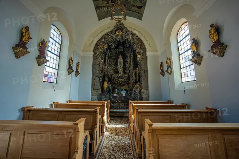 Interior view of a small chapel with wooden benches, statues of saints and a decorated altar, Oberstaufen, Allgäu, Bavaria, Germany