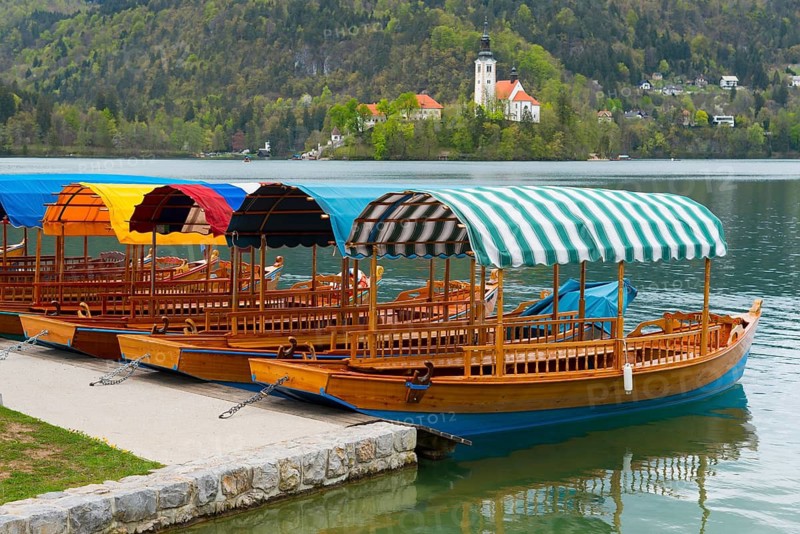 Several colourful boats lying side by side on the shore of a lake against a mountain backdrop, Lake Bled, Lake Veldes, Blejsko jezero, Bled, Veldes, Feldes, Oberkrain region, Gorenjska, Slovenia, Balkans