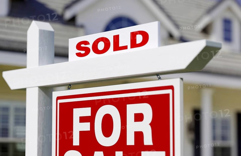 Sold for sale real estate sign in front of new house.