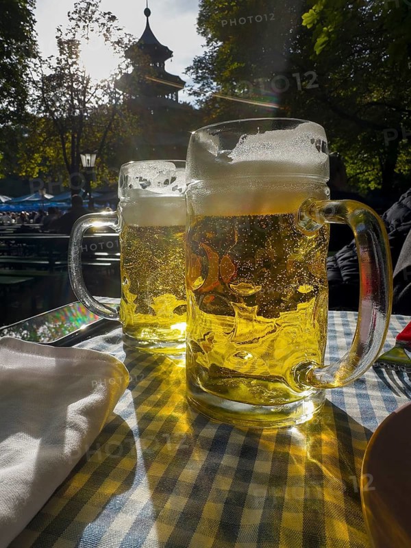 Full beer mugs on a set beer garden table in front of the Chinese Tower, English Garden, Munich, Bavaria, Germany