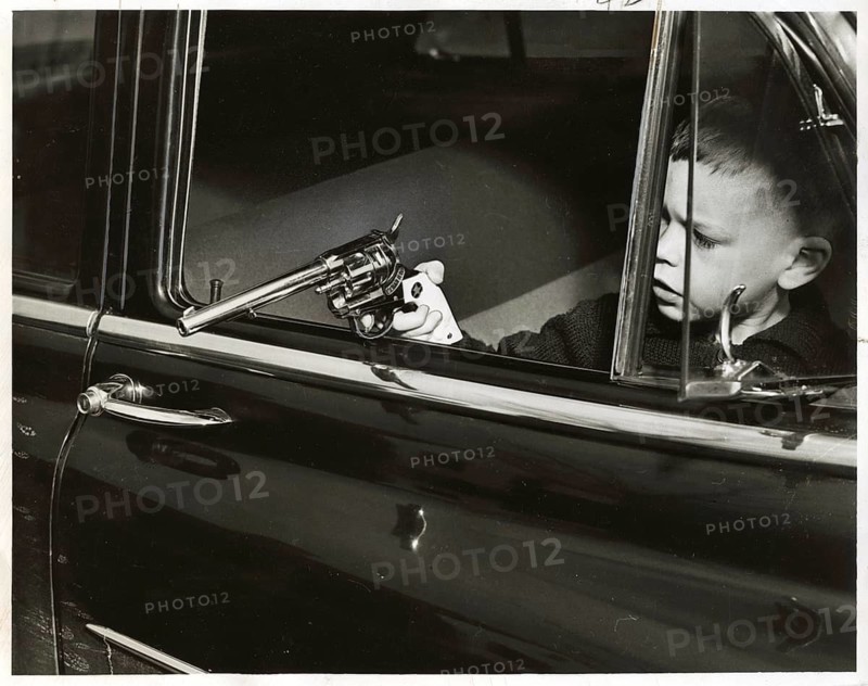 Child, game, pistol, car, A boy holds a toy gun out of a moving car, symbolic of curiosity and danger