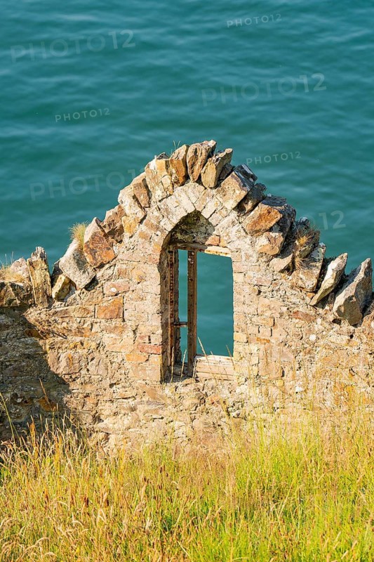 Stone ruin by the sea with an arched window to the water, Howth, Ireland
