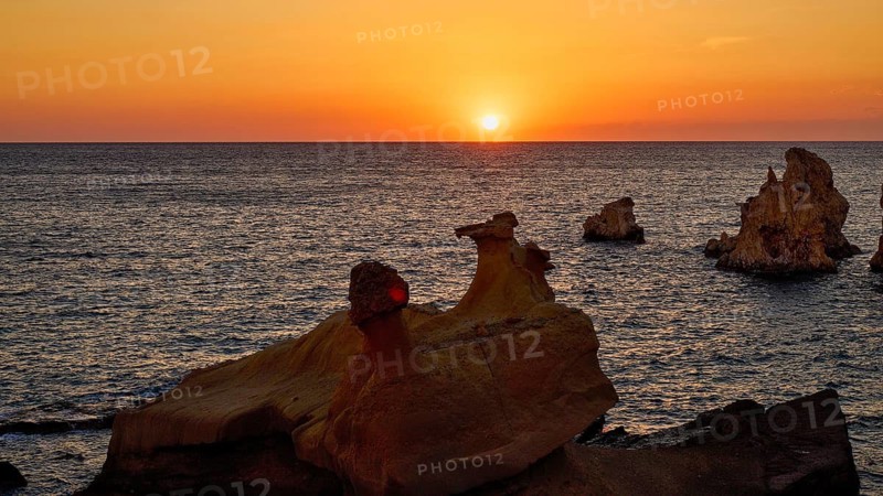 Sunset casts an orange glow over sea and rocks, Aspragremna, White Cliffs, Mavorspilia Beach, Kimolos Island, Kimolos, Cyclades, Greek Islands, Greece