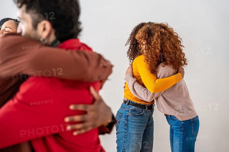 Diverse group embracing in a supportive circle, sharing empathy and comfort in a safe space to promote connection, healing, mental health and emotional well being