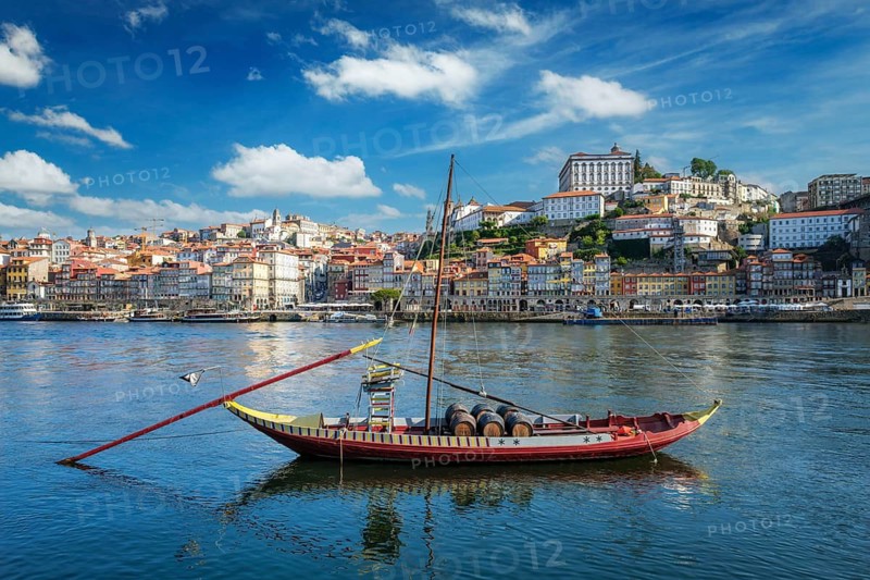 View of Porto city and Douro river with traditional boat with port wine barrels from famous tourist viewpoint Marginal de Gaia riverfront. Porto, Vila Nova de Gaia, Portugal