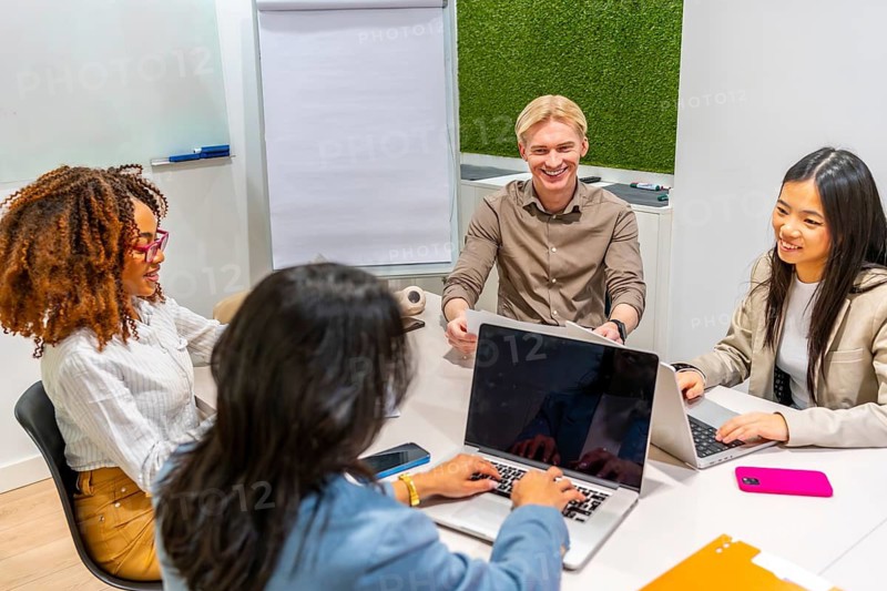 Multi ethnic colleagues using laptops and discussing during a productive meeting in a coworking space