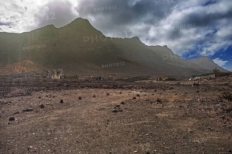 Dramatic mountain landscape with a small, lonely village (Cofete) under a cloudy sky, Pajara, Fuerteventura, Canary Islands, Spain