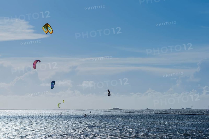Kitesurfing on the North Sea, Lüttmoorsiel, Reußenköge, on the horizon Hallig Nordstrandischmoor, Lorendamm, wind force 6, blue sky, North Frisia, Schleswig-Holstein, Germany