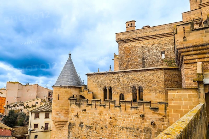 Majestic royal palace of olite rising above the town, showcasing its impressive towers, fortified walls, and medieval architecture under a cloudy sky