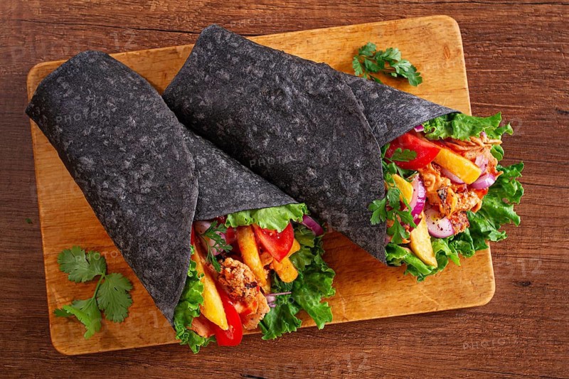Shawarma in black lavash, on a wooden background, chicken shawarma, no people