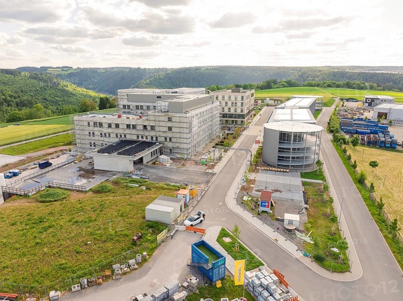 Progressive construction of a building complex along a road with a hilly landscape, construction of the new hospital Gesundheitscampus Calw, Germany