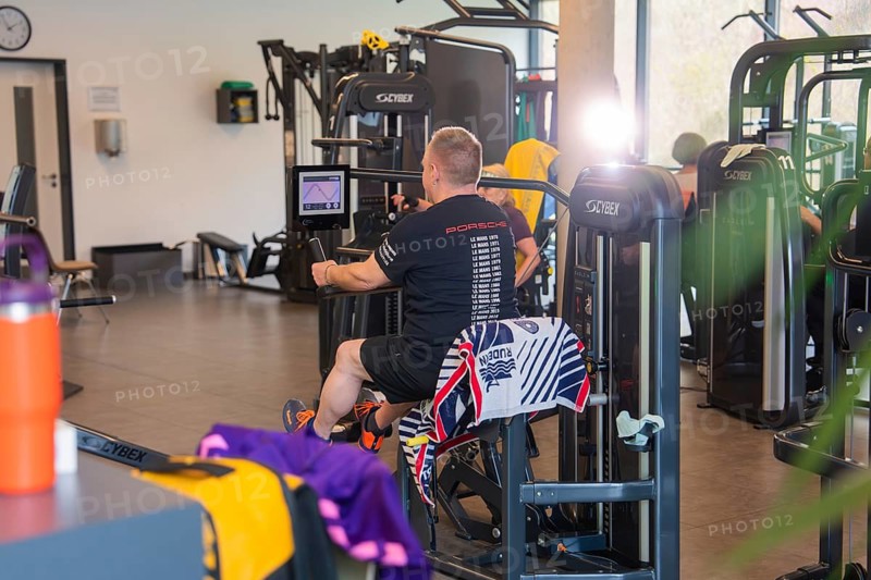 A man works out on fitness equipment with a towel in a lively studio, Fitness TSV Calw, Germany