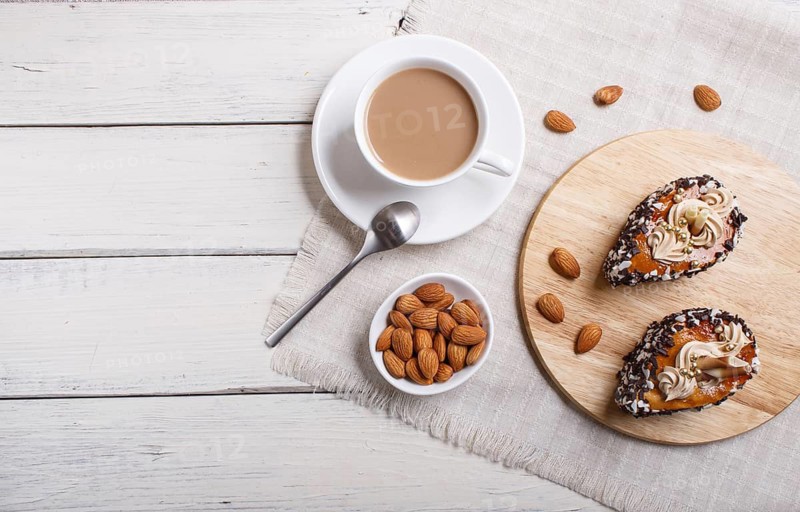 Cakes with chocolate chips and cream decorations on wooden board on white wooden background. with cup of coffee. top view, copy space