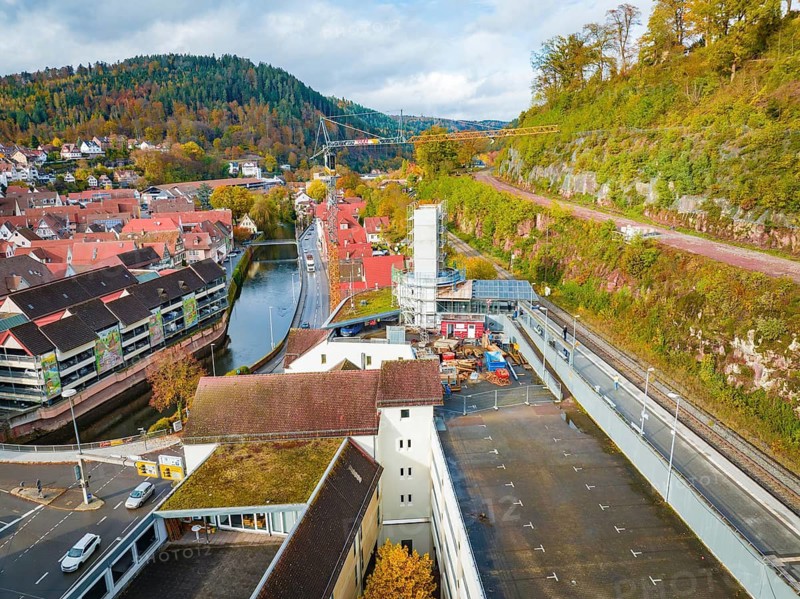 City view with river and construction crane, surrounded by autumnal nature, extension of the Calw central bus station for the new track of the Hermann Hessebahn, Calw, Black Forest, Germany