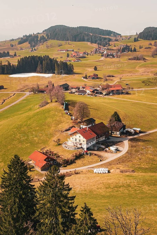 A picturesque alpine landscape shows houses on hills under a clear sky, Oberreute, Allgäu, Germany