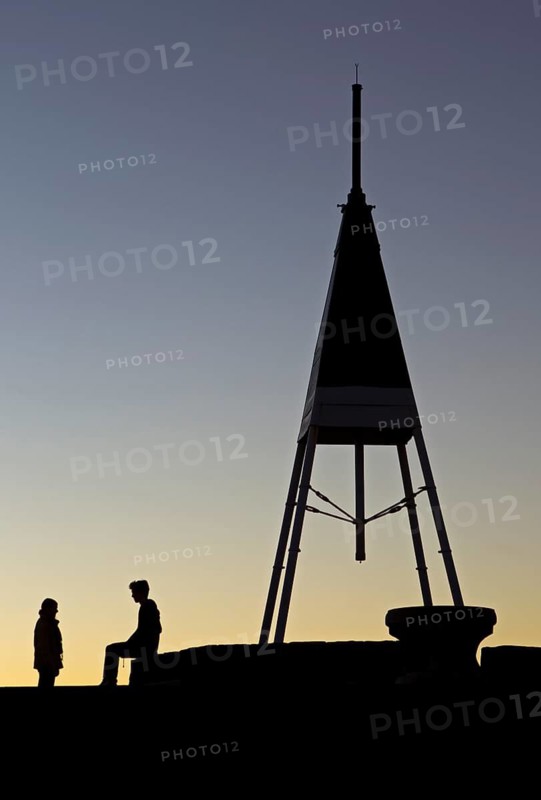 Couple silhouetted beside the trig station on Mount Eden, Auckland, New Zealand