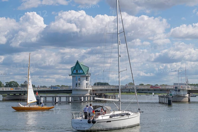 Sailors wait for the Schleibrücke to open, city of Kappeln an der Schlei, fjord, Baltic Sea Fjord, Schlei region, port town, folding bridge, waterside promenade, sailboats, pleasure boats, shipping, maritime culture, tourism, tourist destination, coastal landscape, water, nature, recreation, city history, sights, Baltic Sea coast, Schleiufer, maritime flair, traffic, road closure, bridge, open space, blue sky, Germany