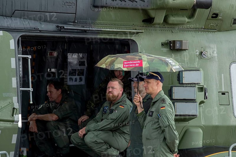 Crew of an NH 90 helicopter holding umbrellas in the rain – International Aerospace Exhibition (ILA), Berlin ExpoCenter Airport, Schönefeld, 10 June 2026