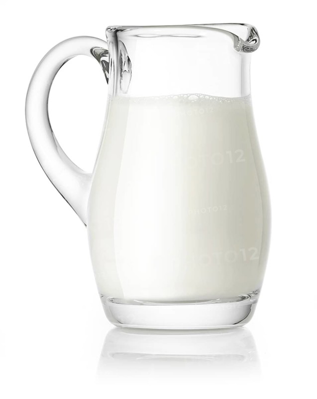 Glass jug filled with milk against a white background, studio shot