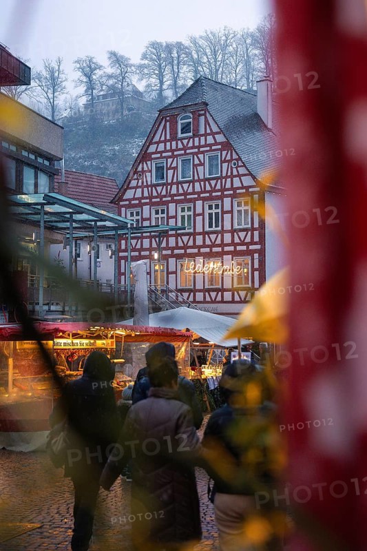 Snow-covered half-timbered house with Christmas market visitors and festive lighting, Christmas market Calw, Black Forest, Germany