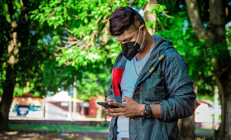 Man with a mask texting with his phone, young man with a mask texting with his cell phone, close up of a young man with a mask texting