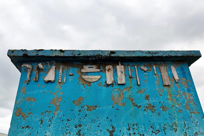 Heavily weathered blue wall, facade, corrosion, peeling paint, various pieces of wood, driftwood, decoration, street art, installation, Andenes, Andoya, Vesteralen, Nordland, Northern Norway, Norway