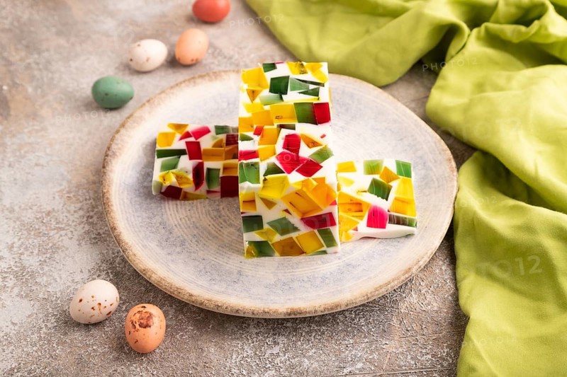 Colored Fruit and milk jelly on brown concrete background and green linen textile, side view, close up, minimalism