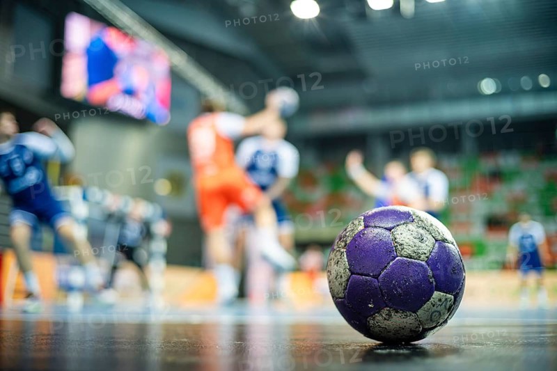The handball ball laiyng on the parquet and handball match in the background in Lubin, Poland