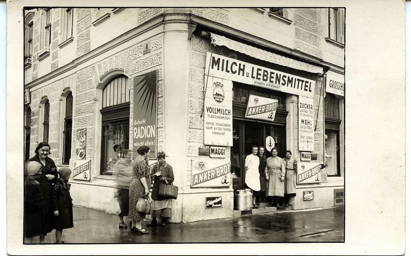Vienna, 2nd district, Engerthstr. 229, Austria, shop, advertising, signs, anchor bread, A grocery store on a street corner with people in front of it, stylish atmosphere, around 1930