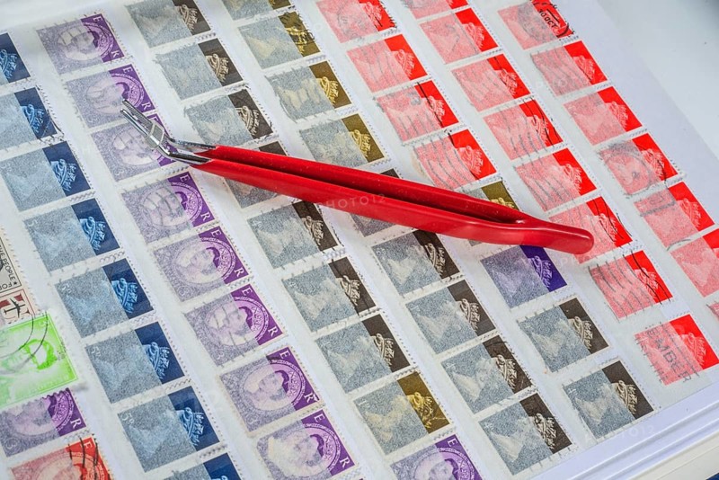 Philately, tweezers on album page with English stamps