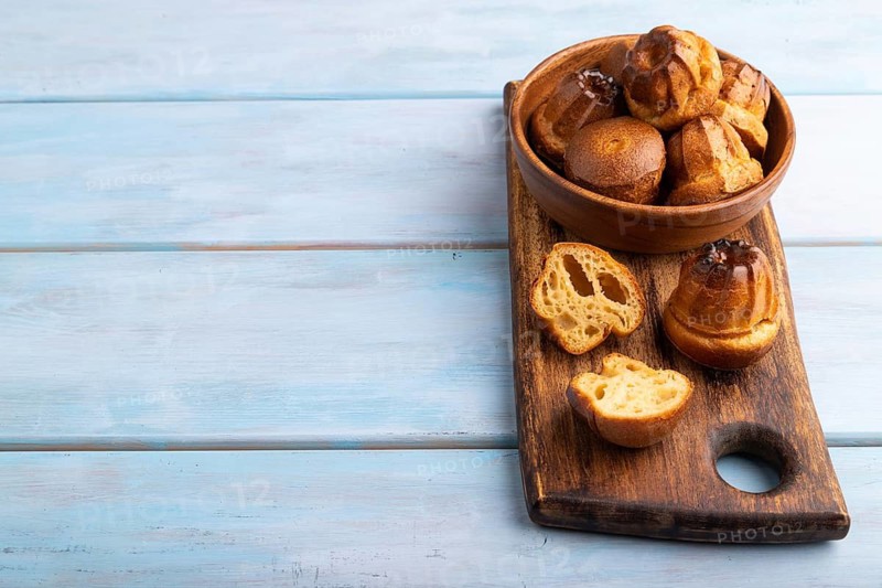 Golden caramelized Canele cookies dessert, on blue wooden background, Copy space, side view