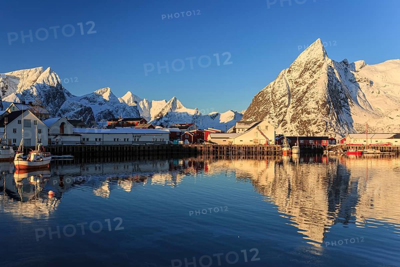 Snow-covered mountains reflected in fjord at sunrise, village, winter, Reine, Moskenesoya, Lofoten, Norway