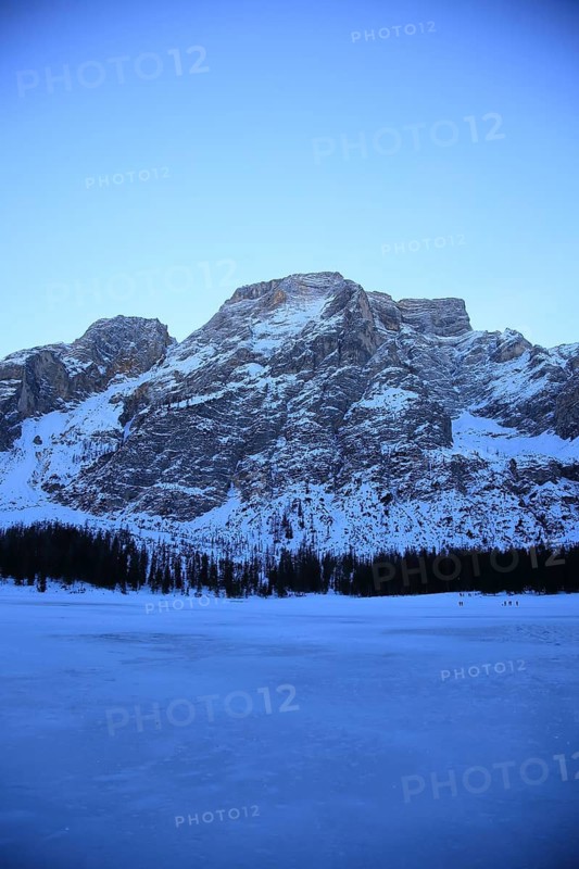 Snowy mountains, a forest in the foreground, cold and quiet with soft evening light, Pragser Wildsee, Lago di Lake Prags, frozen mountain lake in winter, Prags, Lake Prags, South Tyrol, Italy
