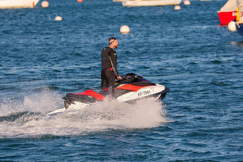 A man rides fast across the water on a jet ski, Howth Harbour, Ireland